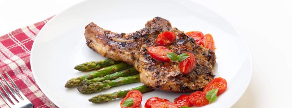 Pork chop with asparagus and tomatoes.